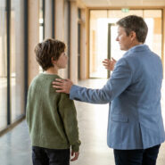Un enseignant rassure un élève dans un couloir d'école moderne et lumineux.