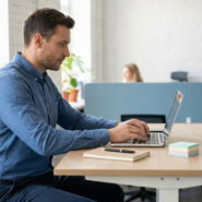 Un homme concentré travaille sur son ordinateur portable dans un bureau moderne et lumineux.