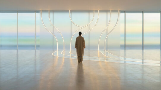 Une personne debout face à un mur lumineux épuré dans un espace minimaliste, symbolisant la sérénité et le calme.