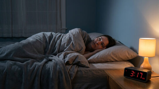 Une femme éveillée dans son lit à 3h17 du matin, semblant anxieuse et incapable de trouver le sommeil.